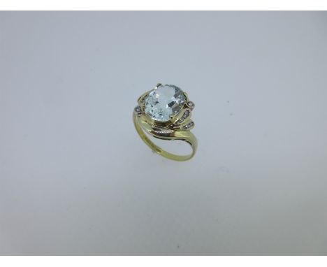 the large oval cut aquamarine between asymmetric shoulders each set with eight round brilliant cut diamonds, held by a crosso