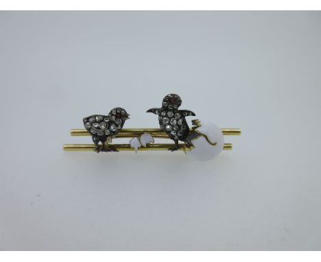 with two parallel bars on which are two chicks, set with rose cut diamonds and ruby cabochon eyes, one emerging from a white 