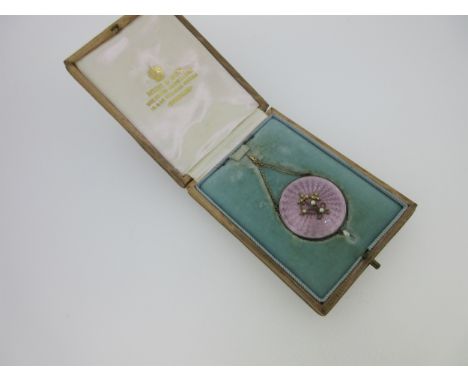 of circular form, the engine turned lilac guilloche enamel with an applied seed pearl set ribbon-tied posy in the centre, and