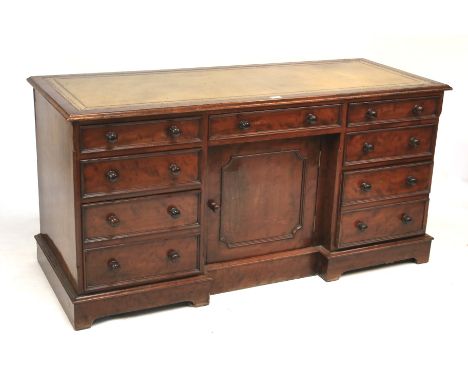 A Victorian mahogany desk. With tooled leather insert to the top, above a central frieze drawer and cupboard flanked by two b