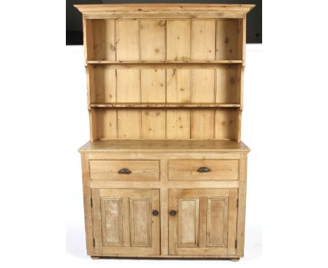 A 19th century and later pine dresser. With paneled back and two open shelves with hooks, the base of two drawers and two pan