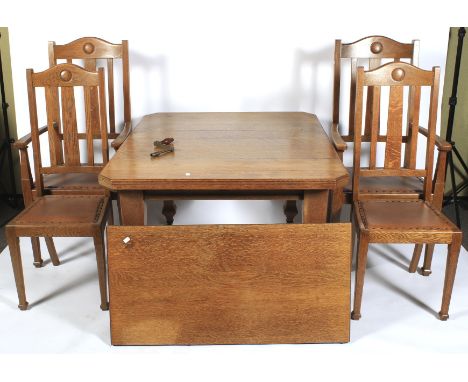An oak Arts and Crafts wind out dining table and chairs. The top with angled corners with extra leaf, raised on square taperi