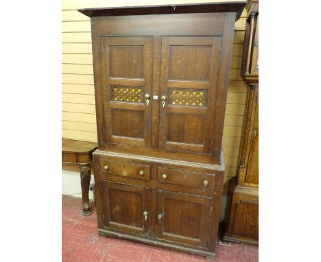 A WELSH ANTIQUE OAK BREAD & CHEESE CUPBOARD, the twin door upper section with pierced fretwork central panels, brass knobs an