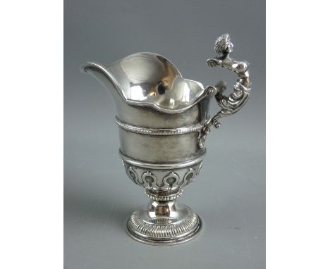 A HEAVY CIRCULAR BASED SILVER CREAM JUG, attractively decorated, having a mask spout and a handle in the form of a maiden and