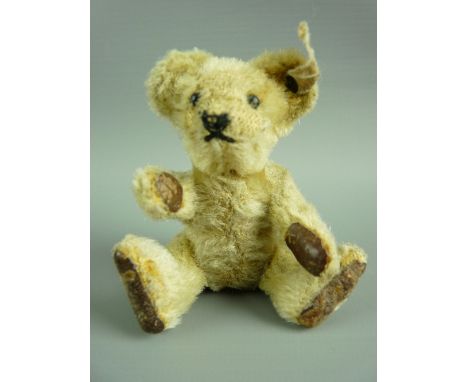 A MINIATURE STEIFF TEDDY BEAR with button eyes, stitched nose and mouth, jointed limbs with leather pads, button and tag to e