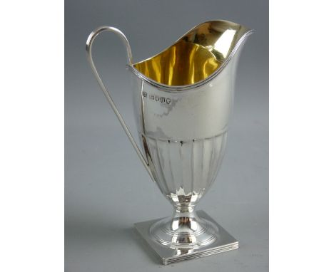 A HALLMARKED SILVER HELMET SHAPED CREAM JUG, London 1883 by William Hutton, the pedestal jug with half segmented body and gil