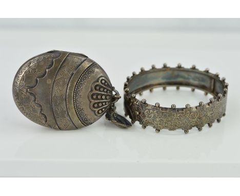 A MID VICTORIAN SILVER LOCKET AND HINGED BANGLE, the locket of oval outline with embossed and engraved decoration to the fron