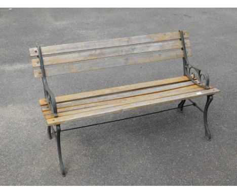 A slatted garden bench, with metal scroll support ends, previously stained, 74cm high, 120cm wide, 45cm deep.