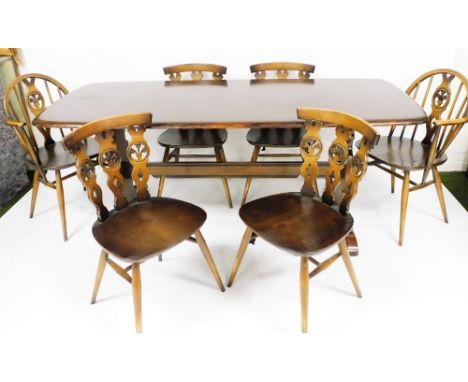 A dark oak Ercol dining room suite, comprising table with six associated chairs two carvers each with wheel back type decorat