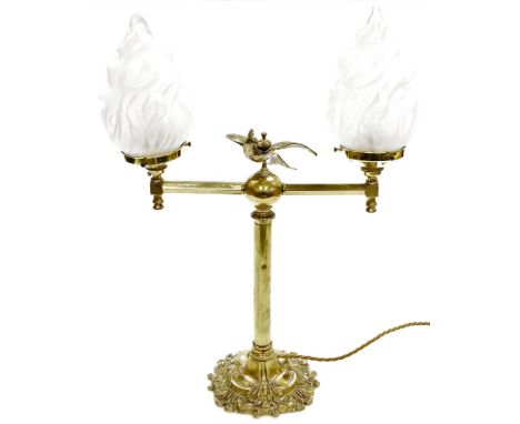 A brass table lamp, with two arm sconce with opaque glass shades, and a central bird on ball motif, converted to electricity,