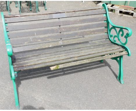 A cast metal garden bench, the ends painted in green, with wooden slats and memorial plaque to back, 80cm high, 130cm wide, 6