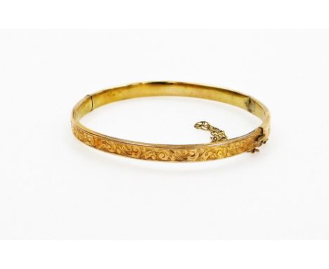 A 9ct gold hinged bangle, of hinged design, the top half with floral etched and scroll detailing, with safety chain, 6cm wide