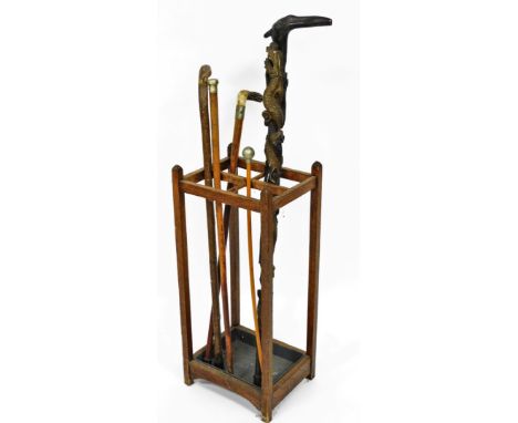 An oak four division stick stand, with an assortment of various walking sticks including an Oriental carved walking stick, an