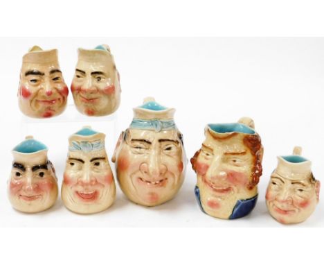A group of French character jugs, with treacle glaze decoration, comprising a graduated set of four, each with ribbon tie top