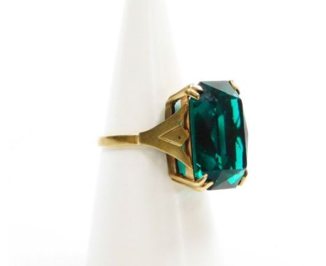 A dress ring, set with large rectangular green paste stone, in four double claw setting, on a raised and pierced basket, yell