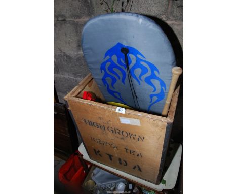 A tea chest containing roller blades, baseball bat, body board.