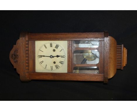 German oak cased wall clock, with scroll pediment above a glazed door, the dial with Roman numerals, 55cm high, 23cm wide