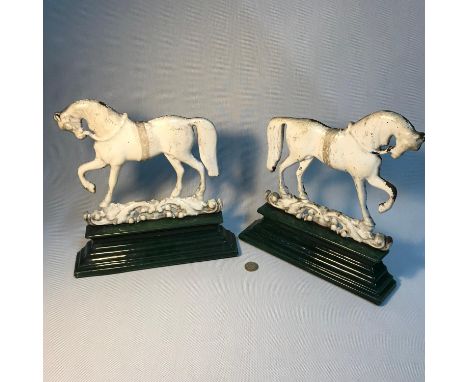 A Pair of antique white and green enamel cast iron door stops of prancing horses. Made by Glasgow foundry Greenlees 