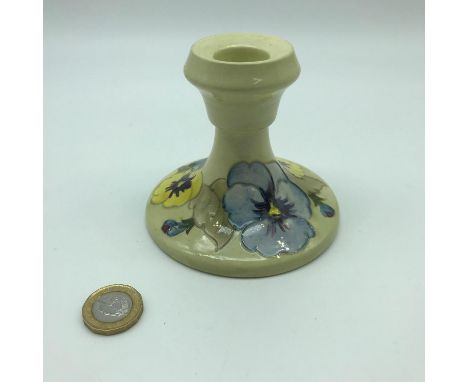 A William Moorcroft floral design candle stick. Impressed marking and sticker to the base. Measures 8.5cm in height 