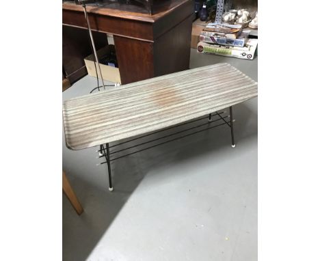 A Retro coffee table designed with a metal base, spar like shelf with white finials and hard plastic table top. 