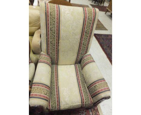 An early Victorian upholstered mahogany show frame library armchair on baluster turned and ringed supports to brass caps and 