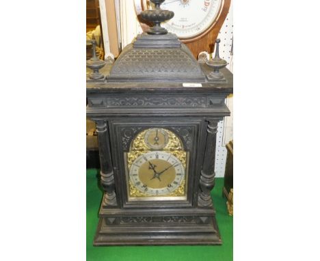 A circa 1900 ebonised cased mantel clock, the domed top with dragon scale decoration over an arched glazed door flanked by tw