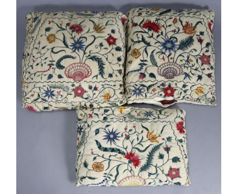 Three late 18th/early 19th century crewel-work scatter cushions of cream ground with all-over multicoloured floral designs ce