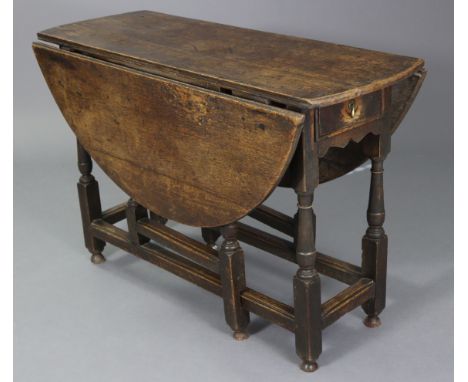 An early 18th century oak gate-leg table, fitted frieze drawer to one end, with shaped apron, half-round drop-leaves &amp; on