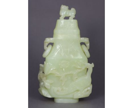 A Chinese pale green jade vase &amp; cover of flattened baluster form, with lion-dog finial &amp; lingzhi ring handles, the b