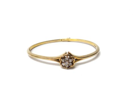 A 9ct gold and diamond set seven stone cluster bangle, claw set with circular cut diamonds, on a clasp with a foldover safety