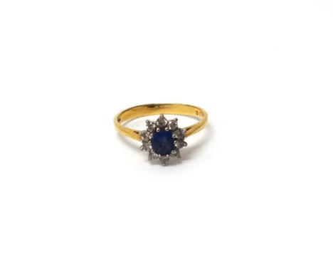 An 18ct gold, sapphire and diamond oval cluster ring, claw set, with the oval cut sapphire at the centre, in a surround of te