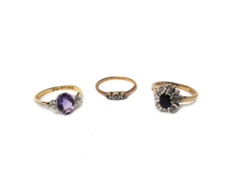 A gold and platinum, amethyst and diamond three stone ring, claw set with the oval cut amethyst between two circular cut diam