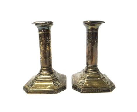 A pair of silver dwarf candlesticks, the cut cornered square loaded bases with reeded borders, the stems decorated with bow s