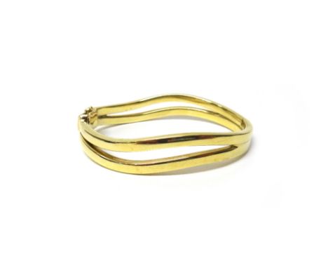 A 9ct gold oval hinged bangle, in a two row curved abstract design, on a snap clasp, with a foldover safety catch, gross weig