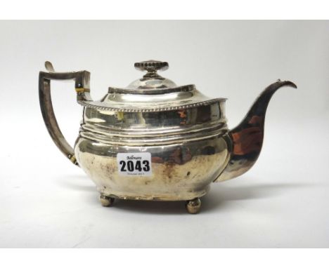 A George III silver teapot, of squat curved form, having a decorated rim, raised on four spherical feet, London 1815, gross w