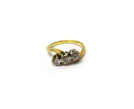 An 18ct gold and diamond set three stone ring, claw set with circular cut diamonds in a crossover design, detailed 18 CT 750,