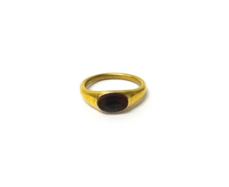 A gold and vary coloured pale brown agate intaglio ring, in the Classical style, the oval intaglio cut as a fish, the ring mo