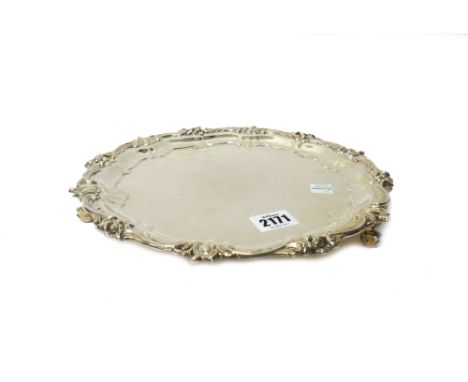 A silver salver, of shaped circular form, in the Chippendale style, decorated with floral motifs to the border, raised on thr
