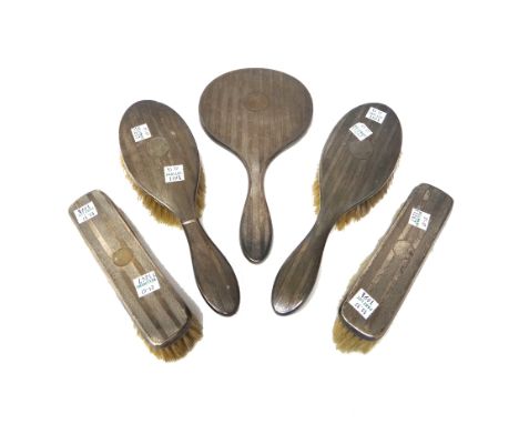 A lady's silver mounted five piece dressing set, comprising; four brushes and a hand mirror, with engine turned decoration Bi