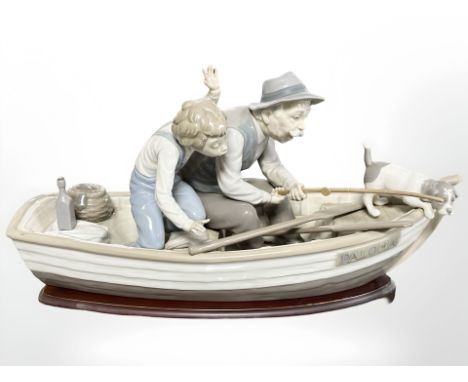 A Lladro figure group of a boy and grandfather fishing in a rowing boat, No. 5215, on wooden plinth, length 39 cm.