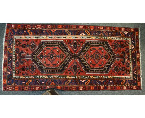 A Hamadan carpet, geometric medallions, in tones of claret and blue, floral motif border and guard stripes, 208cm x 100cm 