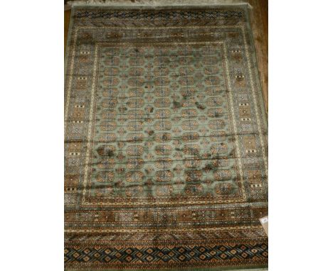 A part-silk Bokhara style green ground carpet, with geometric elephant pad field, multi-bordered and fringed L.190cm W.140cm