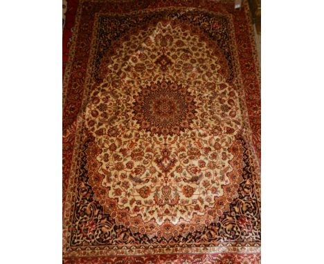 A Persian style part-silk carpet in the Isfahan style, having a black and cream foliate field, multi-bordered and fringed L.2