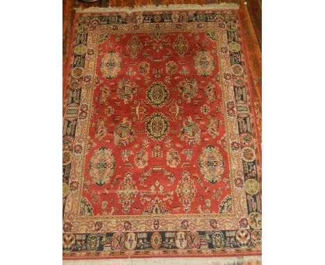 A Persian style red ground carpet, having a geometric foliate field, multi-bordered and fringed L.225cm W.168cm