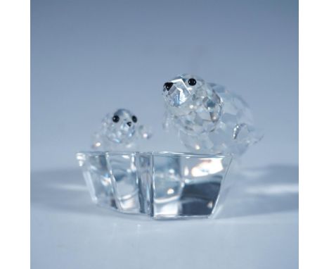 A clear faceted sculpture of a mother seal and her pup, both with black eyes and nose, resting atop a clear smooth ice floe. 