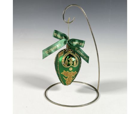 Handcrafted ornament adorned with gold decorative elements that include holly leaves and a stylized fleur de lis crown. The s