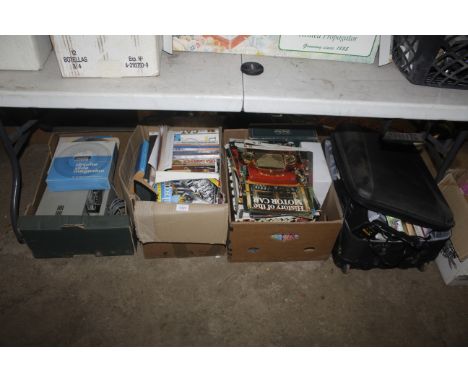 A box containing a slide projector, two cases of slide holders, two boxes of various paperback and hardback books and a suitc
