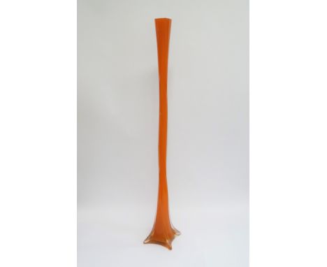 An art glass tall stem vase in orange, encased in clear with twisted body. 90cm high 