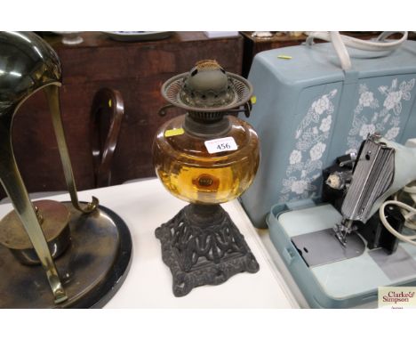 A Victorian oil lamp with cast iron base and amber glass font