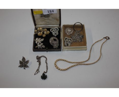 Two boxes containing simulated pearl necklace, a jade coloured pendant on chain and various costume brooches